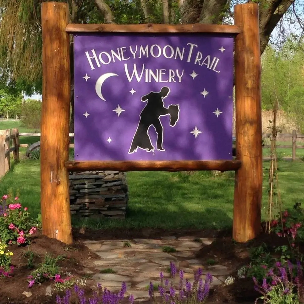 Honeymoon Trail Winery wooden entrance sign surrounded by flowers and greenery