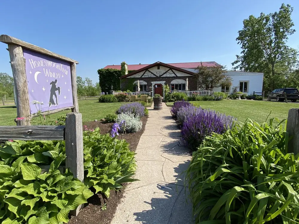 Charming winery building with red roof, surrounded by gardens and a flower-lined pathway
